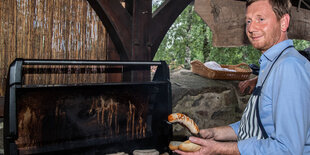 Michael Kretschmer (CDU), Ministerpräsident von Sachsen, grillt beim Auftakt seiner Sommertour im Hof des Landkinos Arnsdorf Bratwürste