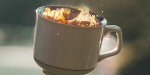 Eine Kaffeetasse aus Porzellan, gefüllt mit Kaffee, in freiem Fall