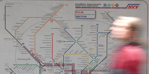 Ein Mann geht an einer Karte mit dem Hamburger Streckennetzplan des Schnellbahn- und Regionalverkehrs entlang.