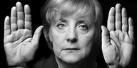 Angela Merkel zeigt ihre Hände neben ihrem Gesicht.