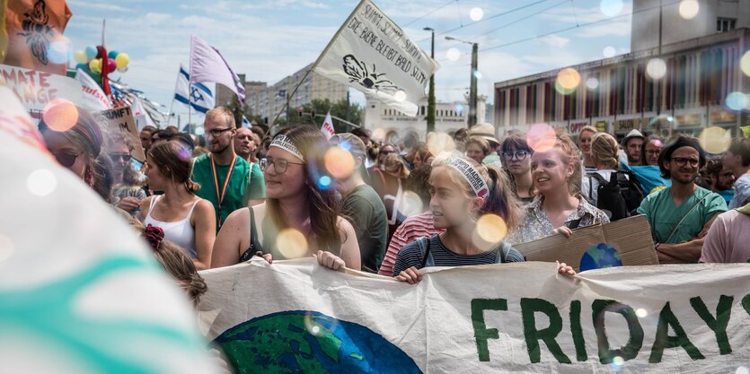 Schülerinnen halten ein Banner mit der Aufschrift "Fridays for Future" dahinter zahlreiche Fahnen