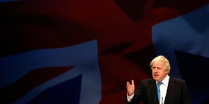 Boris Johnson gestikuliert, im Hintergrund der Union Jack