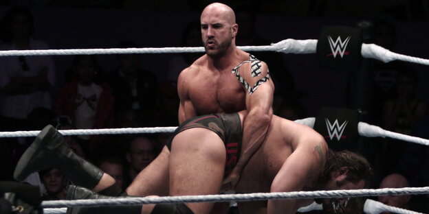 Ein Wrestler hebt einen anderen am Bauch im Ring hoch.