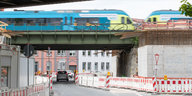 Ein Zug fährt in einer Stadt über eine Brücke, an der gebaut wird