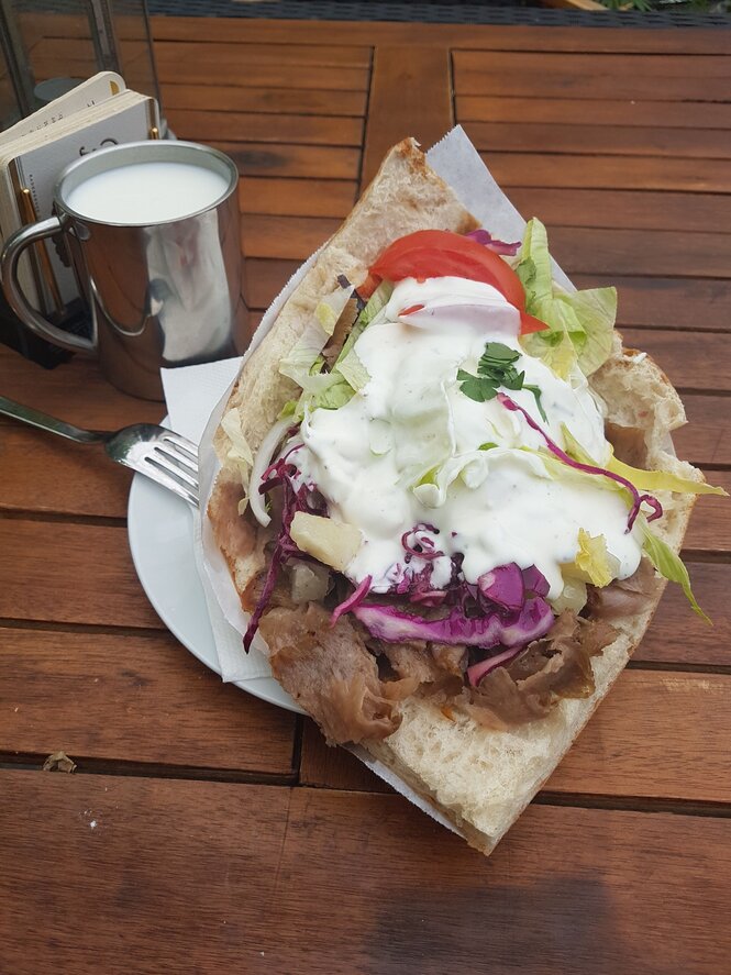 Ein prall gefüllter Döner mit Ananasstücken liegt auf einem Holztisch