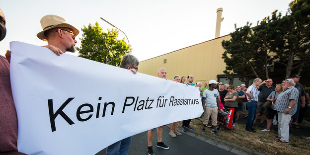 Mäner stehen in Wächtersbach hinter einem Banner mit der Aufschrift "Kein Platz für Rassismus"