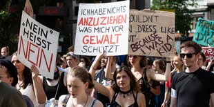 Einige Frauen auf einer Demonstration. Eine von ihnen hält ein Schild mit der Aufschrift "Ich habe nichts anzuziehen, was mich vor Gewalt schützt"