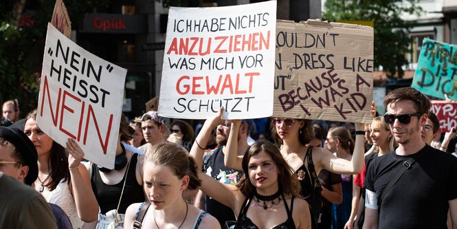 Einige Frauen auf einer Demonstration. Eine von ihnen hält ein Schild mit der Aufschrift 