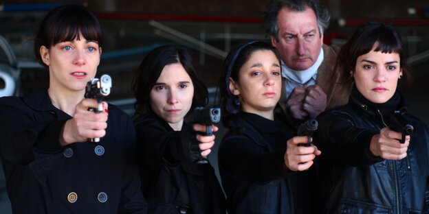 Vier schwarz gekleidete bewaffnete Frauen zielen in Richtug Kamera