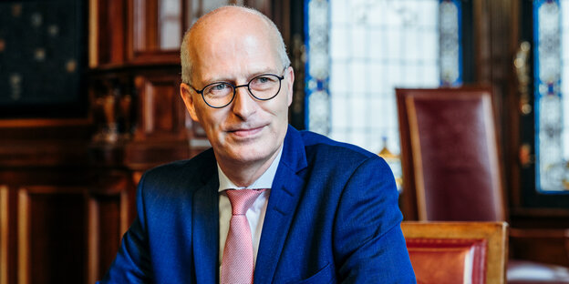 Peter Tschentscher lächelt leicht und guckt nach links. Er trägt ein blaues Sacko und eine weiß-rote Krawatte. Peter Tschentscher lächelt leicht und guckt nach links. Er trägt ein blaues Sacko und eine weiß-rote Krawatte.