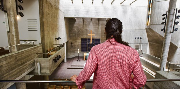 Ein Mann mit rot-weiß kariertem Hemd steht in einer Kirche.