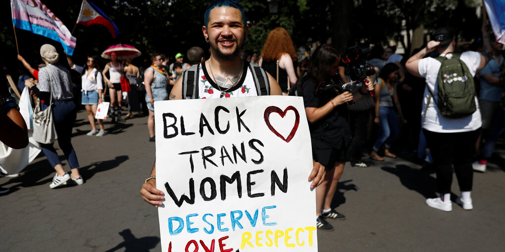 Ein junger Mann wirbt mit seinem Plakat auf einer Demonstration für die Rechte von schwarzen, lesbischen und transgender Frauen