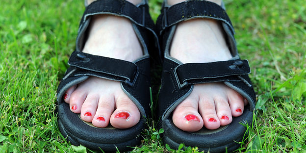 Füße mit rot lackierten Nägeln in Outdoorsandalen Füße mit rot lackierten Nägeln in Outdoorsandalen
