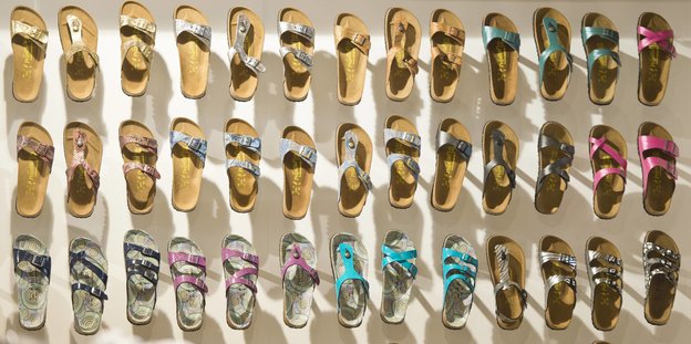 Viele verschiedene Birkenstockschlappen hängen an einer Wand Viele verschiedene Birkenstockschlappen hängen an einer Wand