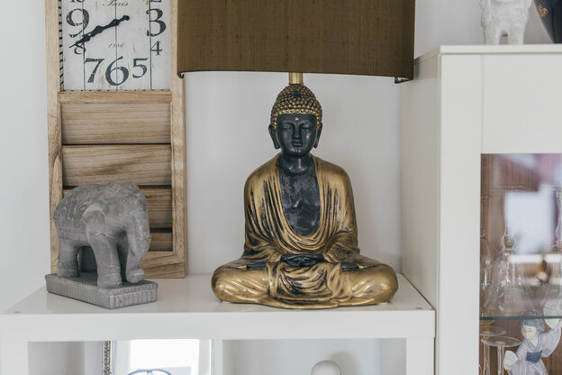 Ein Buddha und ein Elefant aus Stein stehen in einem Regal Ein Buddha und ein Elefant aus Stein stehen in einem Regal