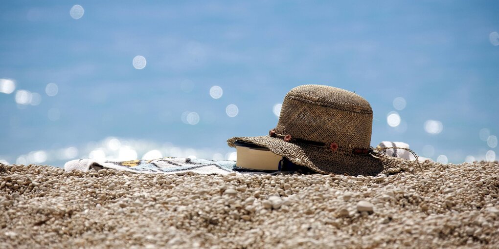 Buch unter Sonnenhut am Strand