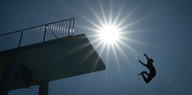 Person springt bei Sonnenschein vom 5 Meter-Turm