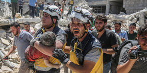 Weißhelme im syrischen Bürgerkrieg tragen nach einem Luftangriff auf einen Markt ein verletztes Kind aus den Trümmern-