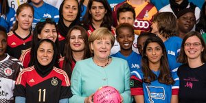 Bundeskanzlerin Angela Merkel hinmitten von vielen Fußballerinnen des Projektes Discover Football