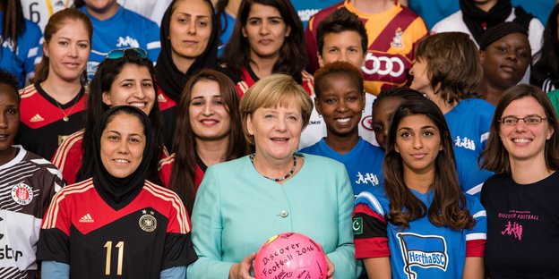 Bundeskanzlerin Angela Merkel hinmitten von vielen Fußballerinnen des Projektes Discover Football