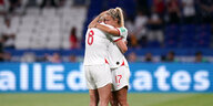 Zwei englische Fußballspielerinnen umarmen sich auf dem Fußballplatz