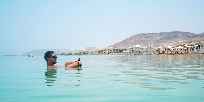 Ein Mann treibt lässig im toten Meer und guckt ans Ufer