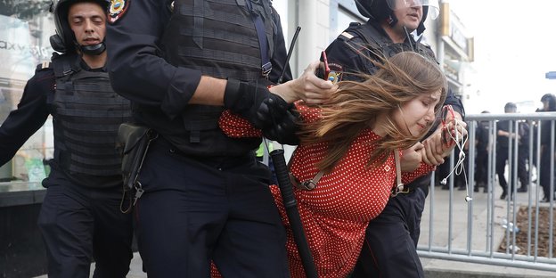 Polizisten führen eine Frau während einer nicht genehmigten Kundgebung im Zentrum von der Stadt ab.