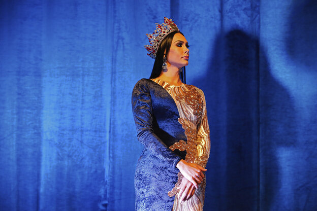 MissTransgender-Gewinnerin trägt eine Krone und steht feierlich vor einem blauen Vorhang