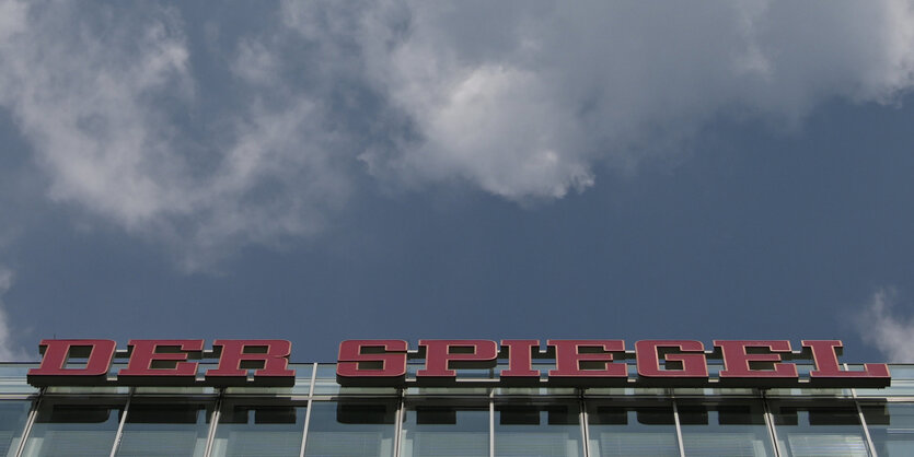 Das Spiegelgebäude mit Schriftzug von unten, darüber blauer Himmel