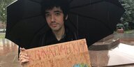 Ein protestierender Mann mit einem Pappschild in der Hand