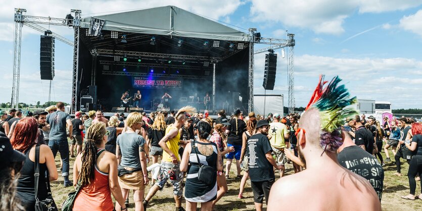 Punk mit Iro steht im Publikum vor einer großen Bühne