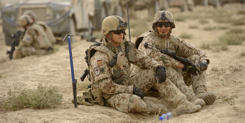 Zwei Bundeswehrsoldaten in Uniform und mit Sonnenbrille sitzen im Sand