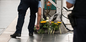 Ein Polizist legt an einer Stelle im Hauptbahnhof Blumen nieder