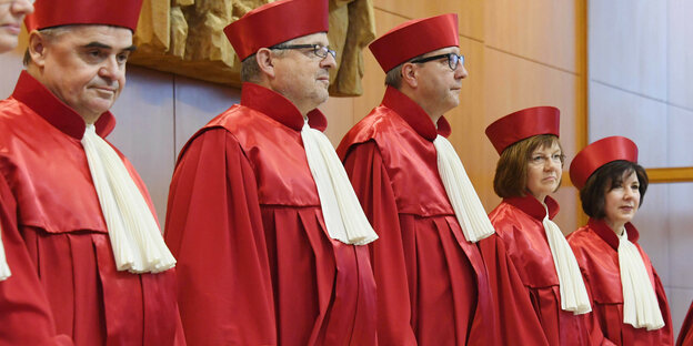 Die Verfassungsrichter stehen in roter Robe im Gerichtssaal