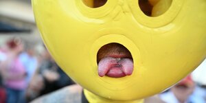 Eine Person steckt ihre gespaltene Zunge durch das Loch einer Maske