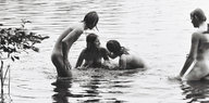 Ein Schwarzweißbild zeigt nackte Menschen beim Baden in einem Gewässer