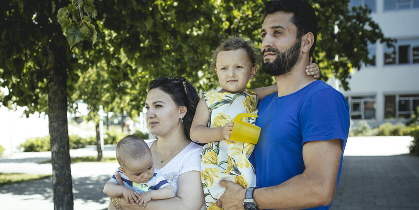 Mann und Frau mit Kleinkindern auf dem Arm