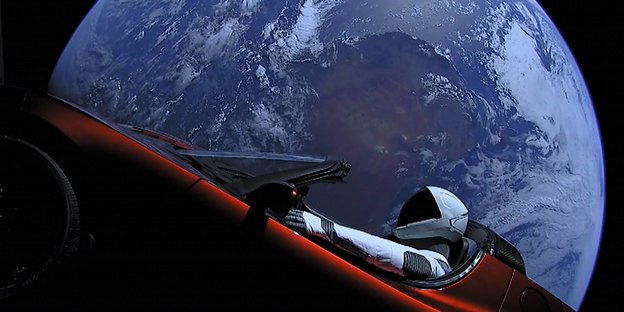 Ein Raumfahrer sitz in einem Auto. Im Hintergrund ist ein Planet zu sehen