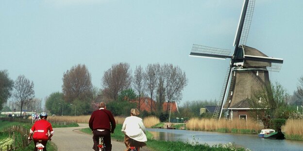 Verkehrswende: Radfahrer fahren an einer niederländischen Windmühle vorbei