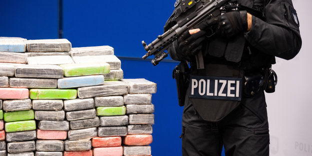 Ein Polizeibeamter steht neben sichergestellten Kokainpaketen