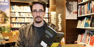 Schriftsteller Marko Dinic in einer Buchhandlung mit aufgeschlagenem Buch in den Händen