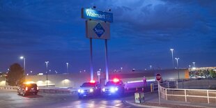 Polizeiwagen blockieren die Zufahrt zu einem Walmart. Es ist dunkel