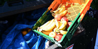 Ein Mitarbeiter eines Supermarktes bringt Obst zu einem Container