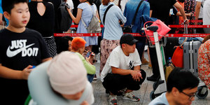 Passagiere stehen am Flughafen in Hongkong in einer Schlange