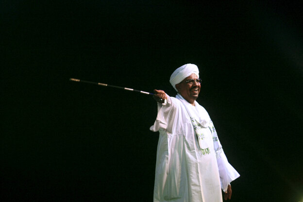 Omar Al Bashir weiß gekleidet vor schwarzem Hintergrund, schwingt einen Stab
