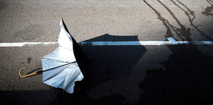 Ein Regenschirm liegt kaputt auf einer Straße in Hongkong