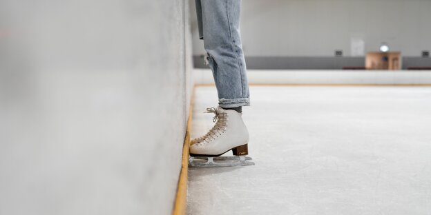 Blick auf die Schlittschuhe von jemandem, der an die Wand in einer EIslaufhalle. Blick auf die Schlittschuhe von jemandem, der an die Wand in einer EIslaufhalle.