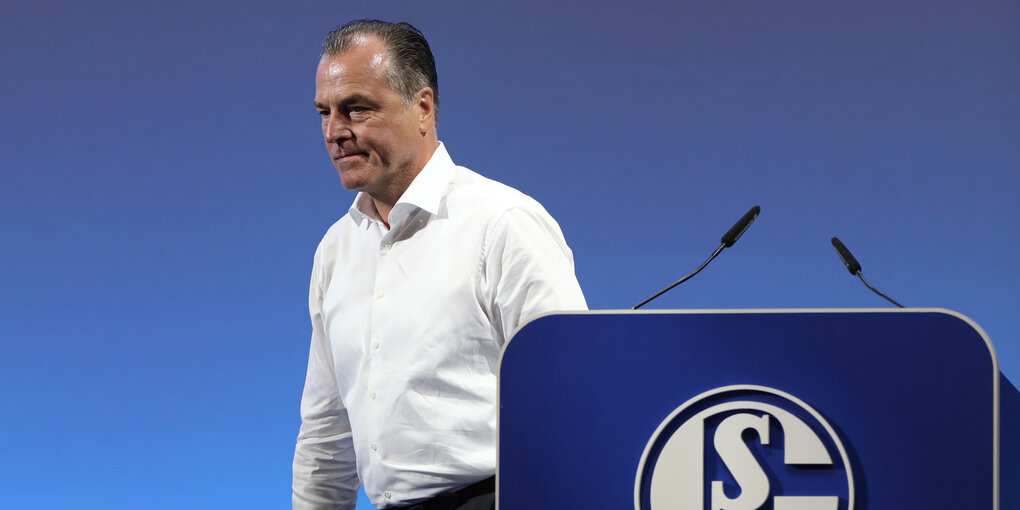 Tönnies entfernt sich gerade von einem Rednerpult mit Schalke-Logo vornedrauf. Die Wand im Hintergrund ist königsblau