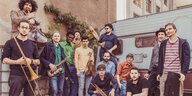 Dreizehn Männer mit Instrumenten stehen auf einem Hinterhof: Banda Comunale.