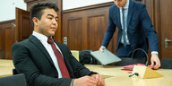 Asif N. sitzt in Anzug im Gerichtssaal, schick gekleidet